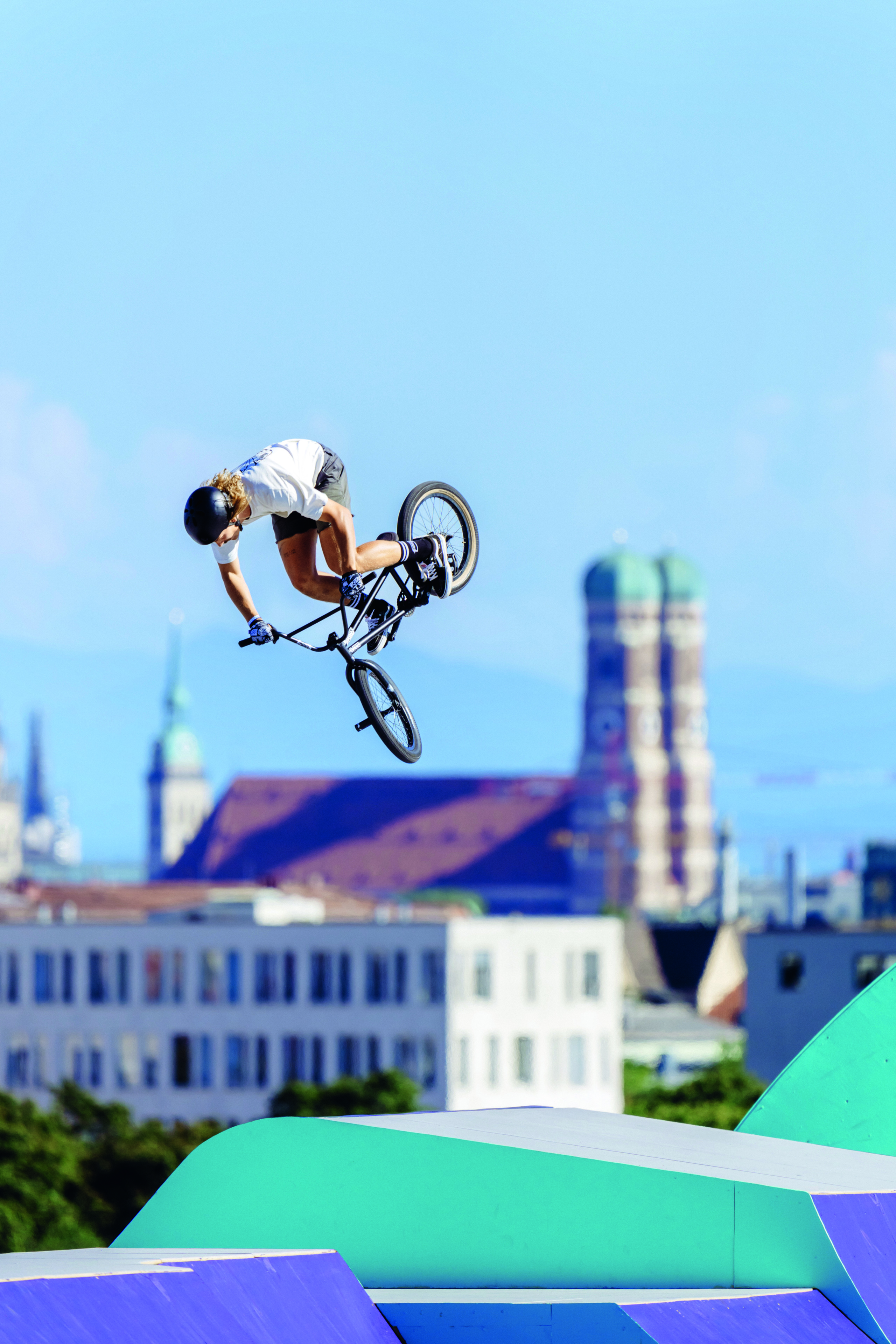 BMX-Sportler in der Luft, im Hintergrund die Frauenkirche in München