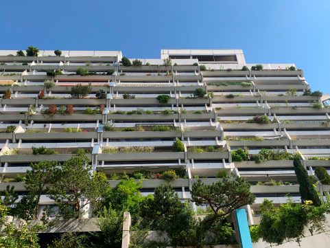 Fassadenansicht des Olympischen Dorfes in München mit Grünpflanzen auf den Balkonen