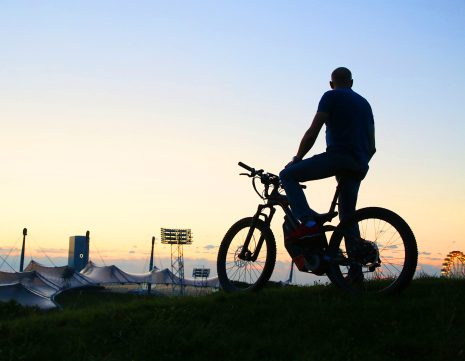 Radfahrer bei Sonnenuntergang auf dem Olympiaberg mit Blick auf das Olympiastadion